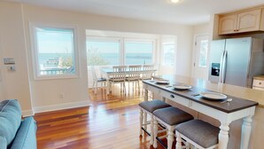 A kitchen with a view of the sea, wooden flooring, white cabinetry, and a dining area with chairs and a table. - Bayfront with Gulf and Pool Access (Port Saint Joe)