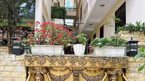 A hotel entrance with a decorative gold relief, potted plants, and a stone wall. - Le Petit Paris Hotel  (Cam Ly - Da Lat)