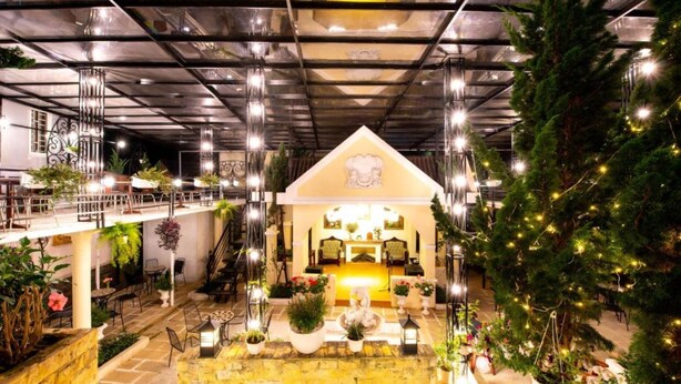 A spacious indoor area with a central seating area, multiple levels, and a large Christmas tree. - Le Petit Paris Hotel  (Cam Ly - Da Lat)
