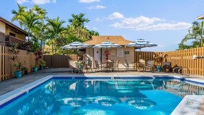 A swimming pool with a wooden deck, outdoor seating, and palm trees. - Summer Deal Kona Condo with Private Lanai Pool and Fast WiFi (Kailua Kona)