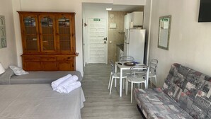 A room with a bed, a sofa, a wooden cabinet, a dining table with chairs, and a kitchen area with a refrigerator. - Benal Beach resort Benalmadena Malaga pools and slides wifi parking, (Benalmádena)