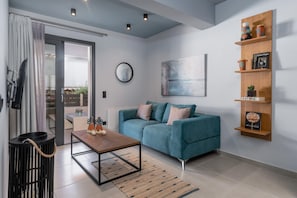 Un soggiorno moderno con un divano color petrolio, un tavolino, una mensola in legno con oggetti decorativi e un grande quadro astratto appeso alla parete.