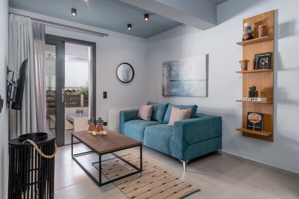 A modern living room with a teal sofa, a coffee table, a wooden shelf with decorative items, and a large abstract painting on the wall.