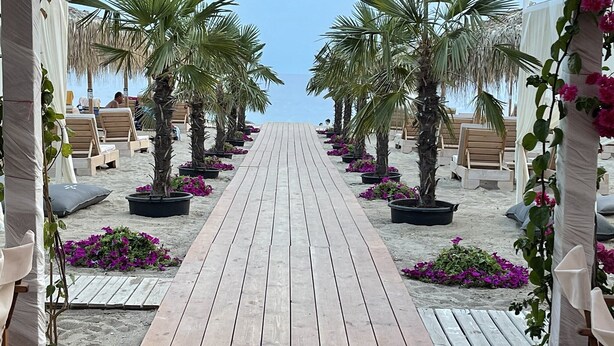 A beach walkway lined with palm trees and lounge chairs, leading towards the sea. - HERACLEA SUITES (Nea Propontida)