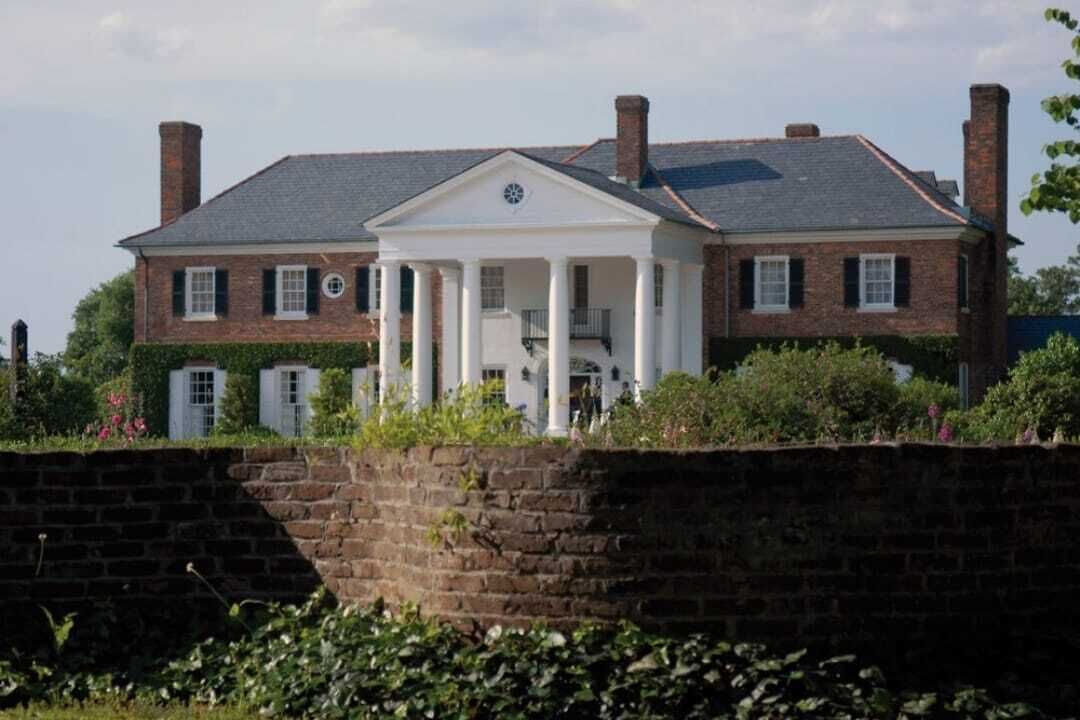 A large brick building with a central white structure featuring columns and a pediment.