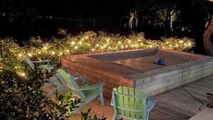 An outdoor hot tub area with wooden decking and green Adirondack chairs. - 12 Abalone Alley by Avantstay Close to Beach w/ Pool & BBQ (Isle of Palms)