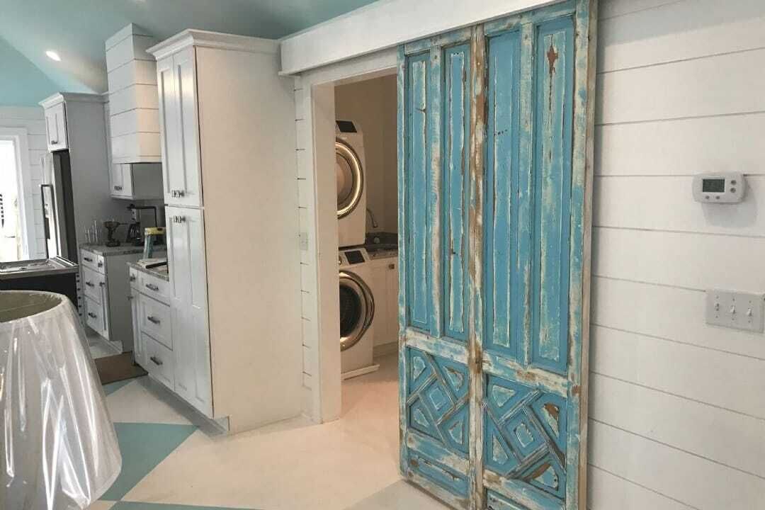 Une buanderie équipée d’un lave-linge et d’un sèche-linge, avec une porte bleue et un thermostat fixé au mur.