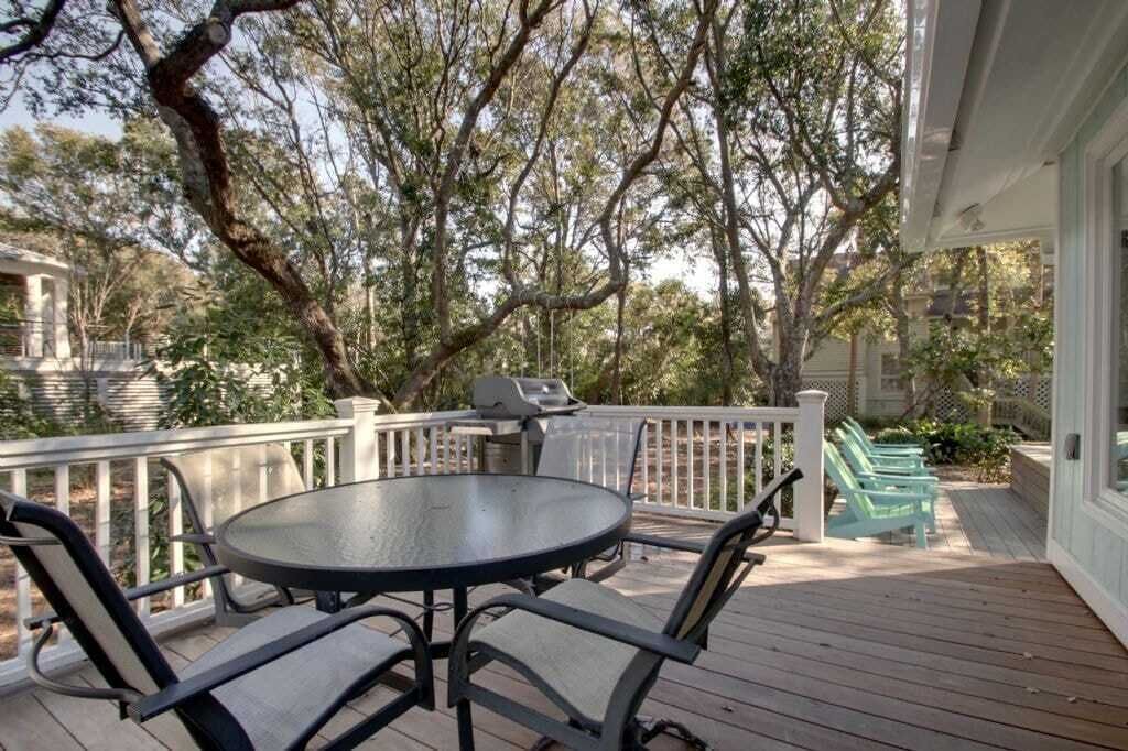 Una terraza techada al aire libre con una parrilla, una mesa redonda y sillas.