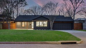 A single-story house with a garage, a well-maintained lawn, and a tree in front.