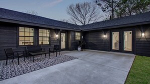 A modern building with a covered patio area featuring a seating arrangement and a concrete floor.