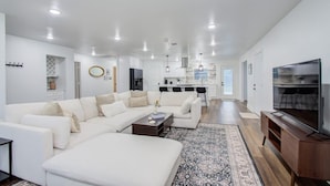 A modern living room with a sectional sofa, a coffee table, and a TV stand.