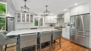 A modern kitchen with a large island, stainless steel appliances, and a view of the outdoors.