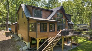 A two-story wooden house with a deck and a staircase leading to the upper level.