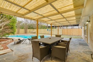 An outdoor patio with a covered seating area, a pool, and a stone floor. - Heart of Dallas - Mansion with Backyard Pool Oasis (Dallas)