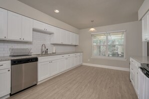 A kitchen with white cabinets, a dishwasher, a window with blinds, and a pendant light. - Heart of Dallas - Mansion with Backyard Pool Oasis (Dallas)