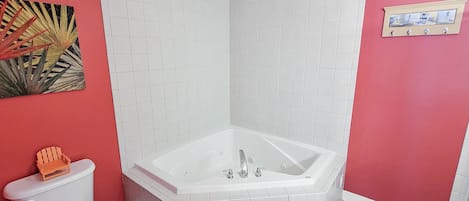 Kylpyhuone, jossa on valkoinen kylpyamme, wc ja punainen seinä.
