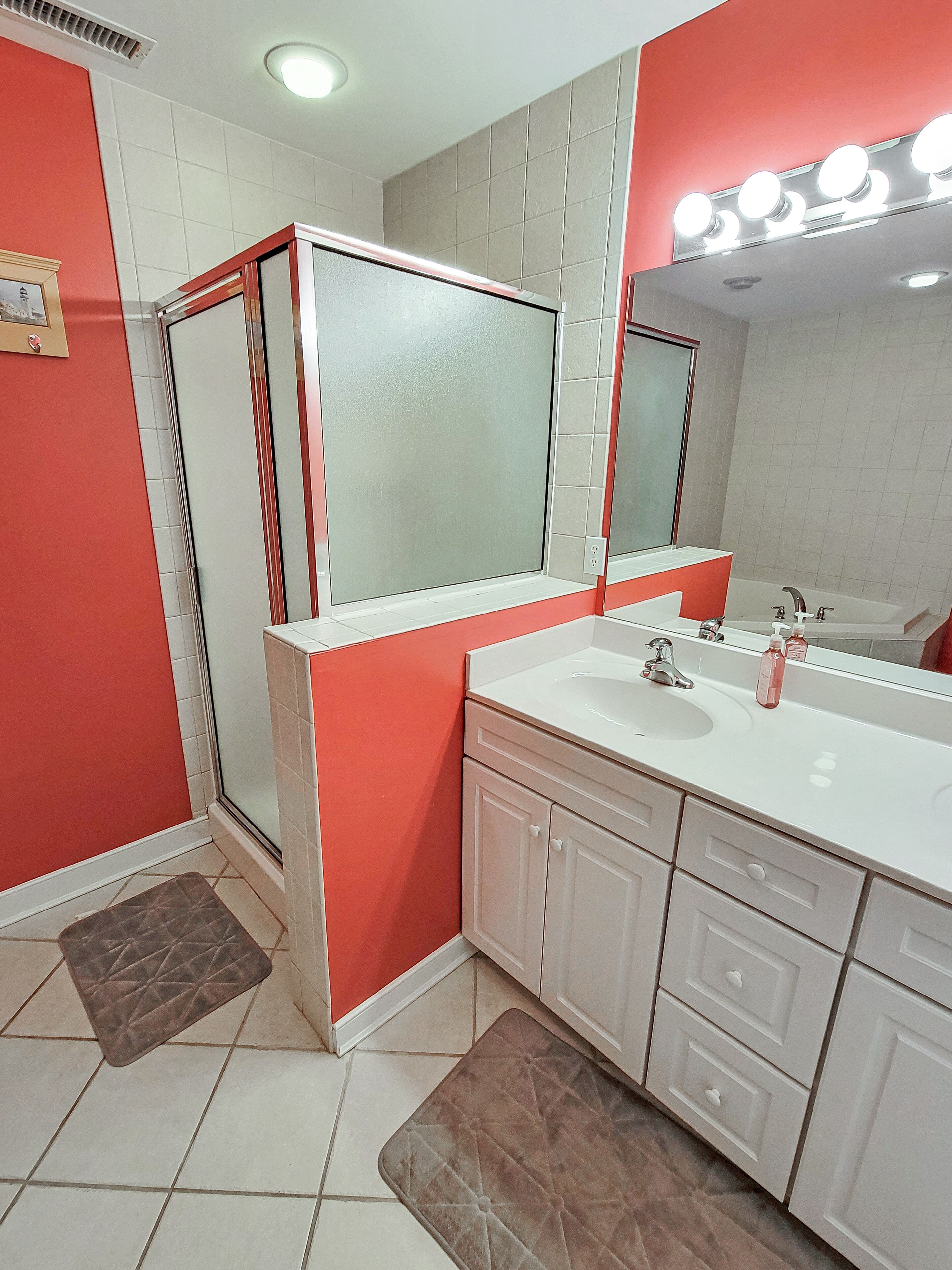 Un bagno con lavandino bianco, uno specchio e cabina doccia.