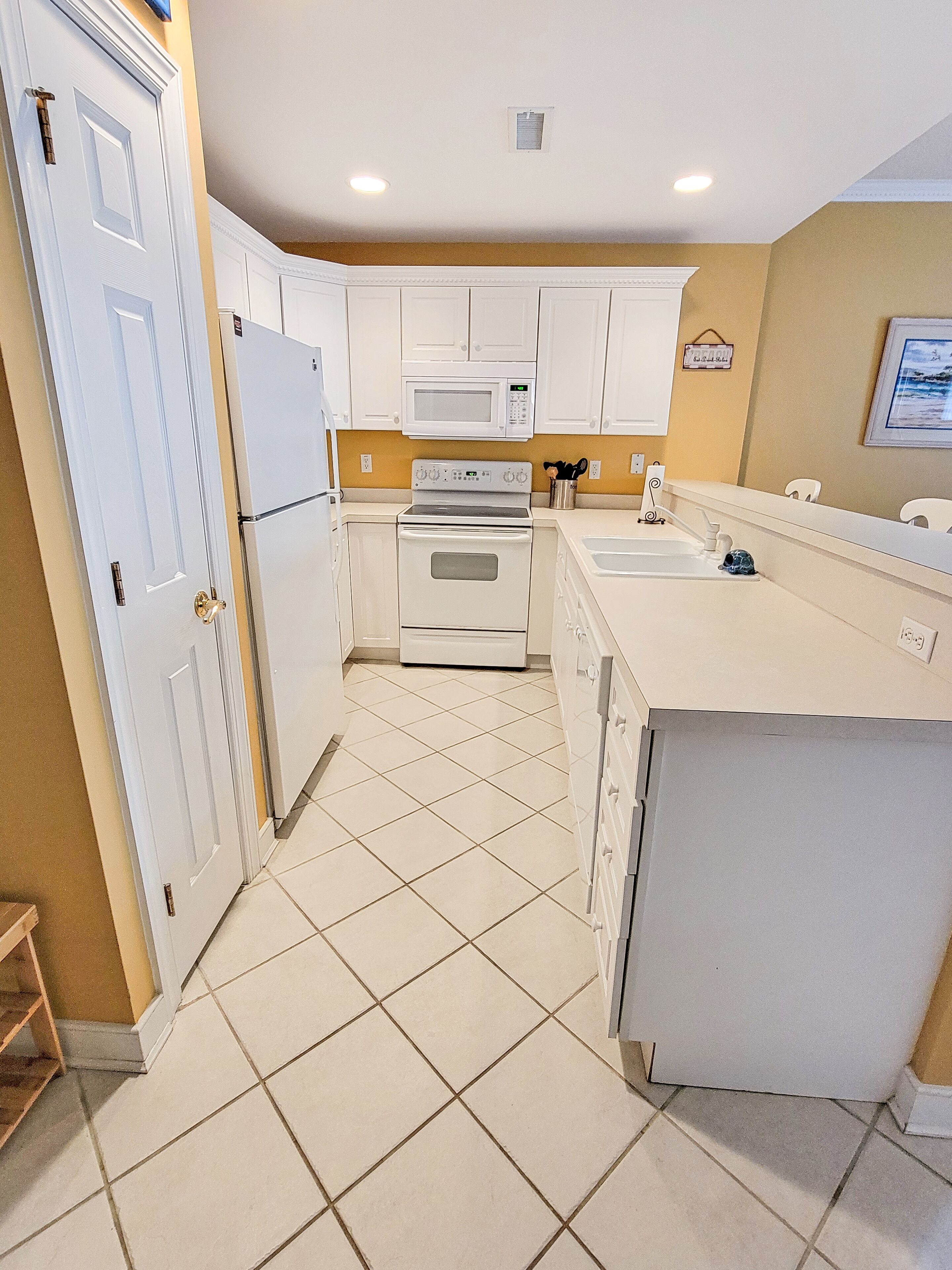 A kitchen with white cabinets, a microwave, an oven, and a sink.