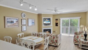 A living room with a fireplace, a television, and a dining area with a table and chairs.