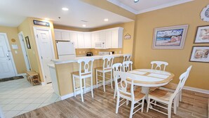A kitchen with white cabinets, a microwave, and a dining area with a white table and chairs.