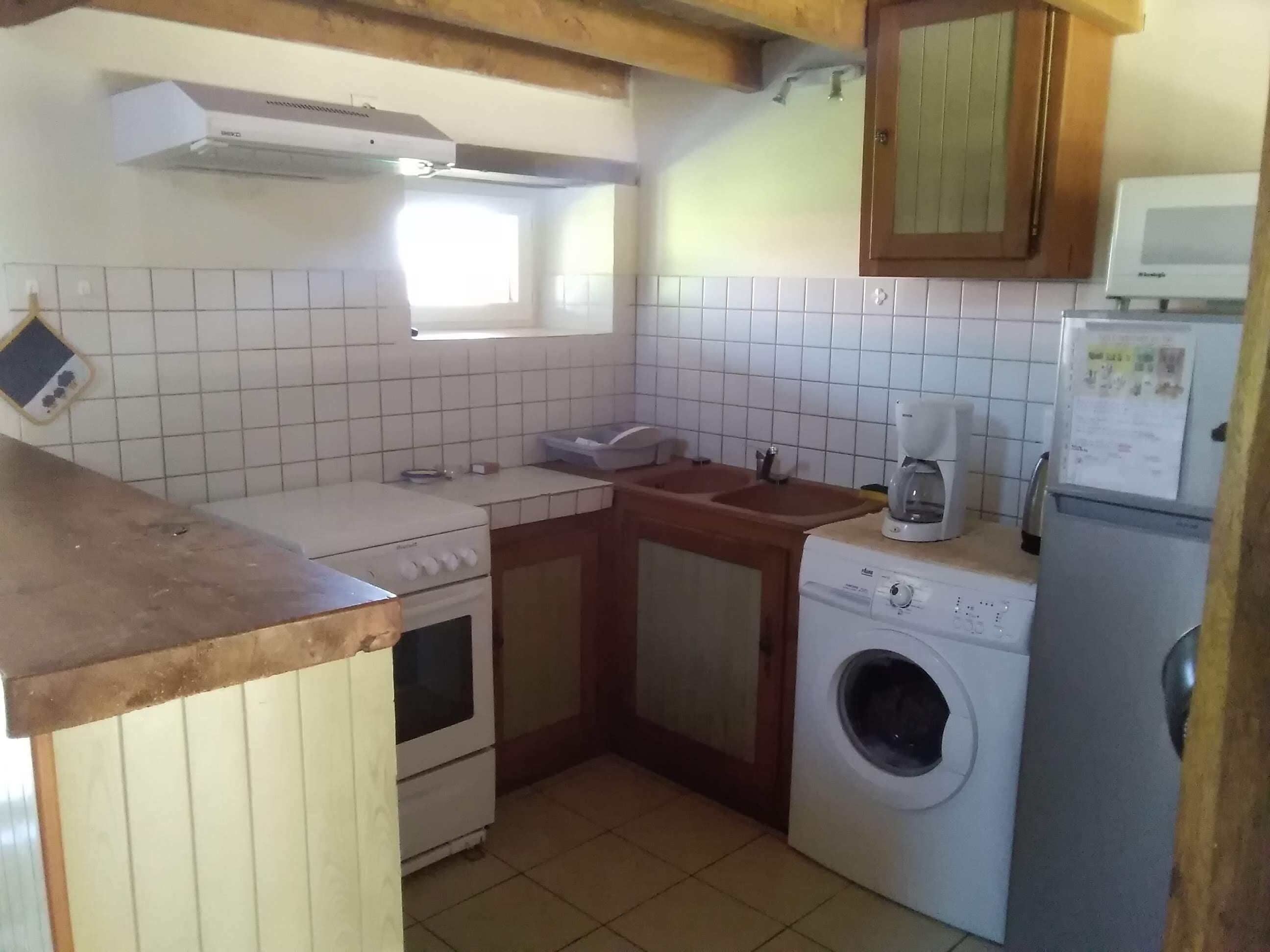 A compact kitchen with a stove, sink, washing machine, and a microwave.