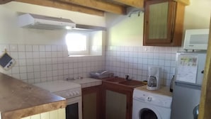 Ett kompakt kök med spis, diskho, tvättmaskin och mikrovågsugn.