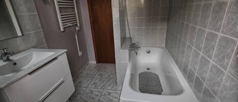 Un baño con bañera, lavamanos y espejo.