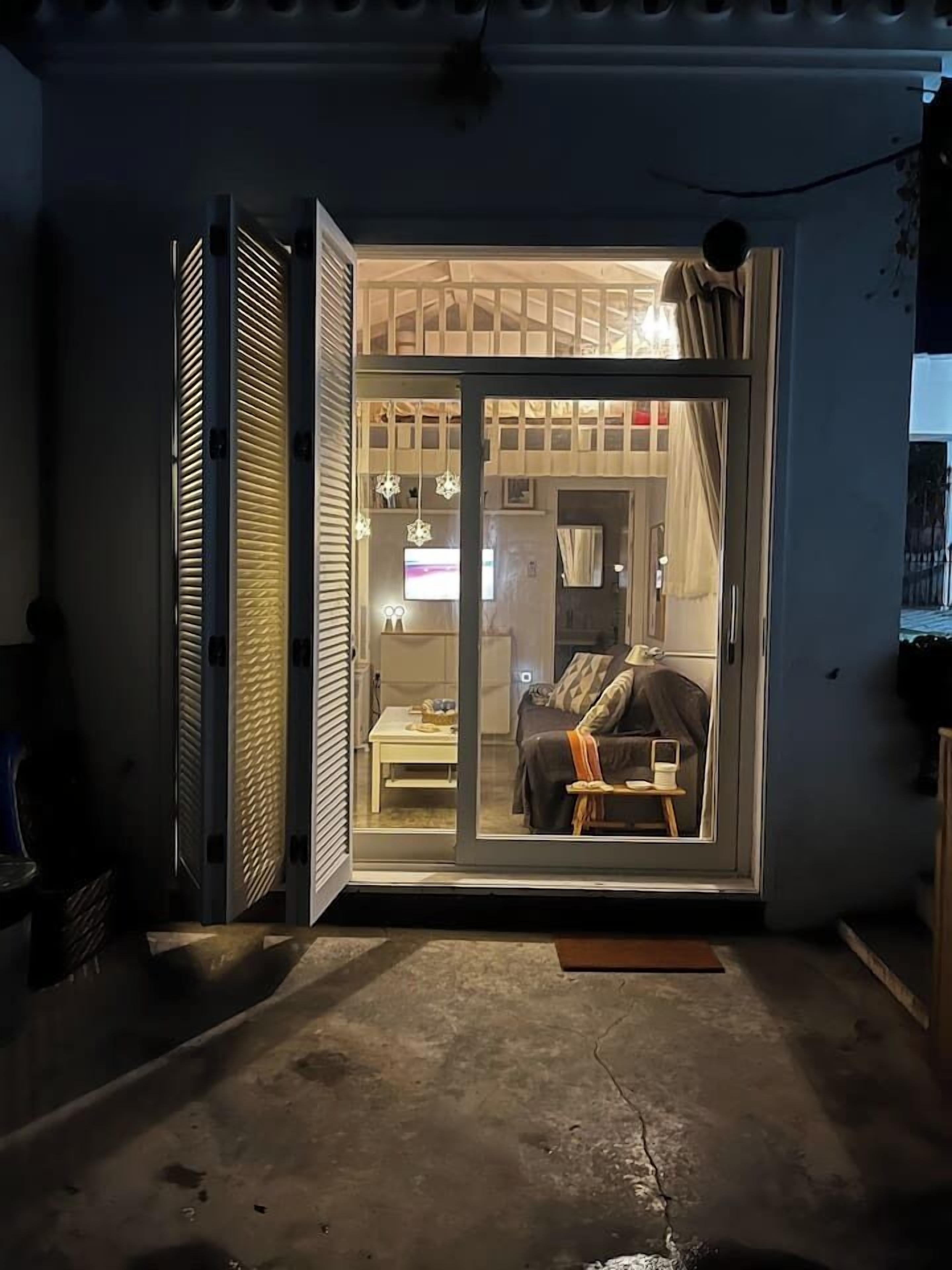 Une pièce dotée d’une porte-fenêtre coulissante, d’un lit, d’une petite table et d’un téléviseur.