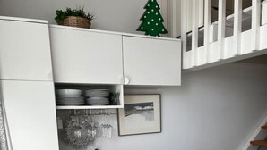 A compact kitchen with a white cabinet, a wooden countertop, a small dining table, a basket of blue and white ornaments, and a staircase. - Guest house on the beach in La Torre Verde (El Puerto de Santa María)