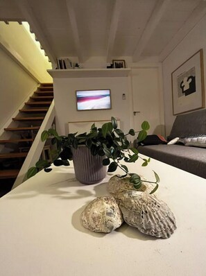 Relax in this stylish living room with a sofa, flat-screen TV, and a staircase leading to an upper level.