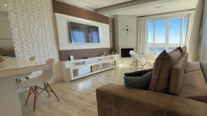 Ein modernes Wohnzimmer mit Flachbildfernseher, Kamin und Sofa.