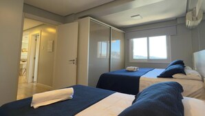 Ein Schlafzimmer mit zwei Betten, einem Kleiderschrank, einem Fenster mit Blick und einer Tür zu einem anderen Raum.