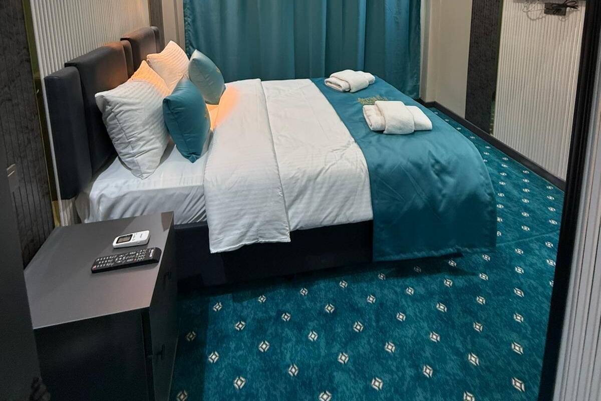 Habitació d'hotel amb un llit, una taula de nit amb telèfon, una làmpada al sostre i un televisor fixat a la paret.