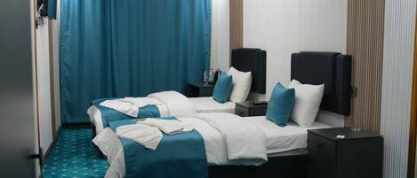 A hotel room with two beds, a blue carpet, and a modern ceiling light fixture.
