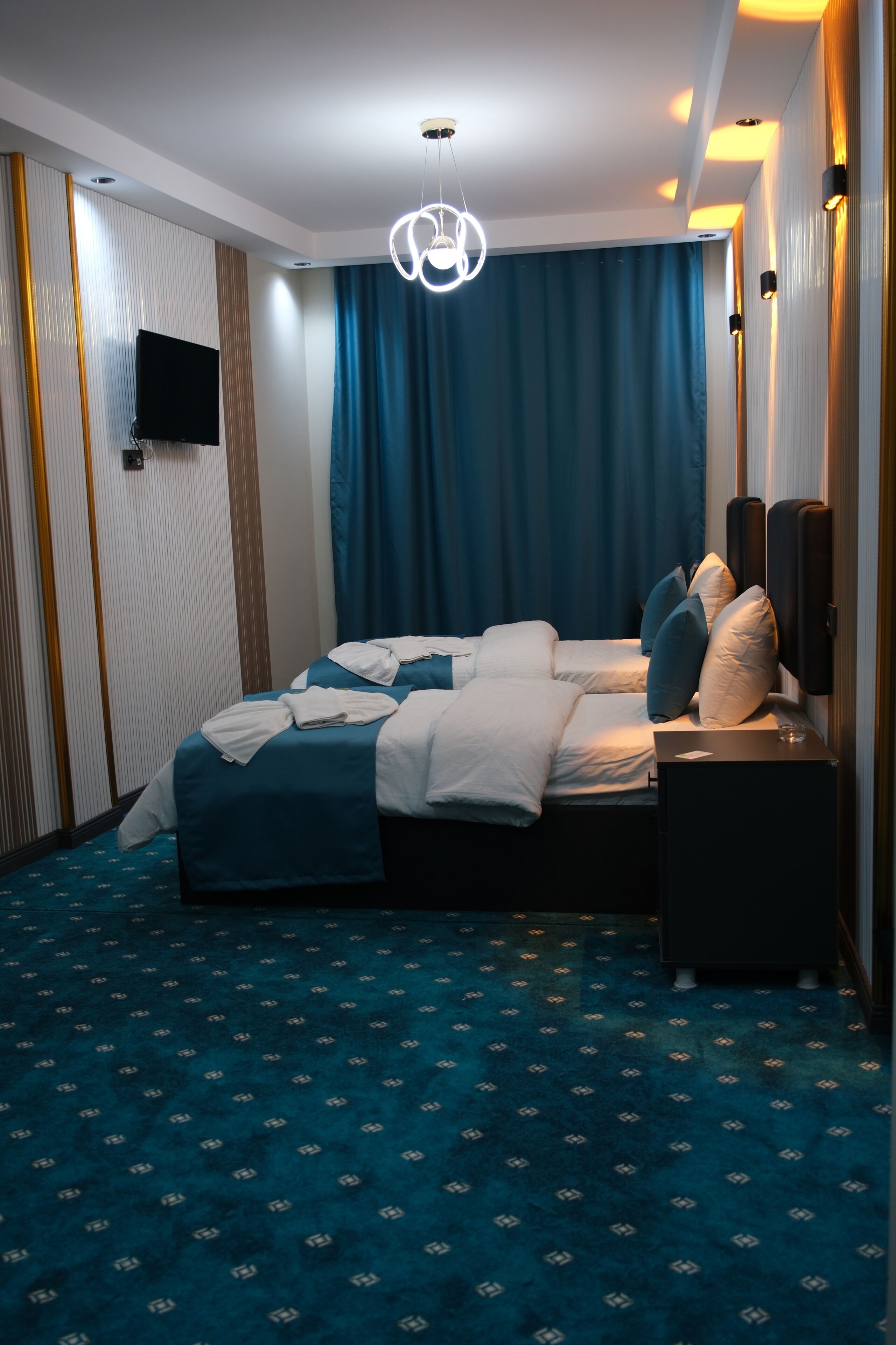 Ett hotellrum med en säng, en platt-TV, ett sängbord och en TV som är monterad på väggen.