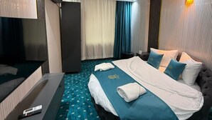 Una habitación de hotel moderna con una cama grande, un televisor de pantalla plana y un minibar.