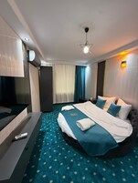Egy modern szállodai szoba, melyben egy nagy ágy, egy síkképernyős televízió és egy minibar található.