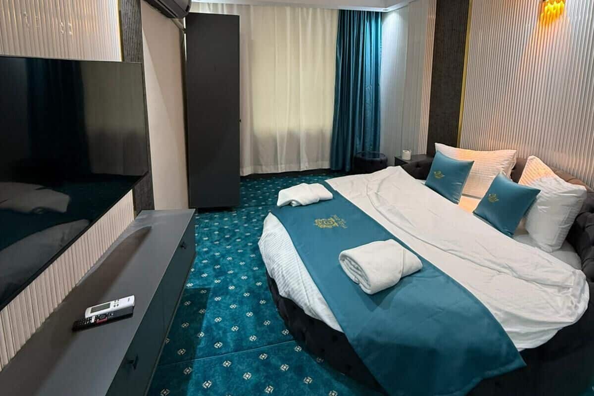 Habitació d'hotel amb llit, televisió, escriptori i llum al sostre.
