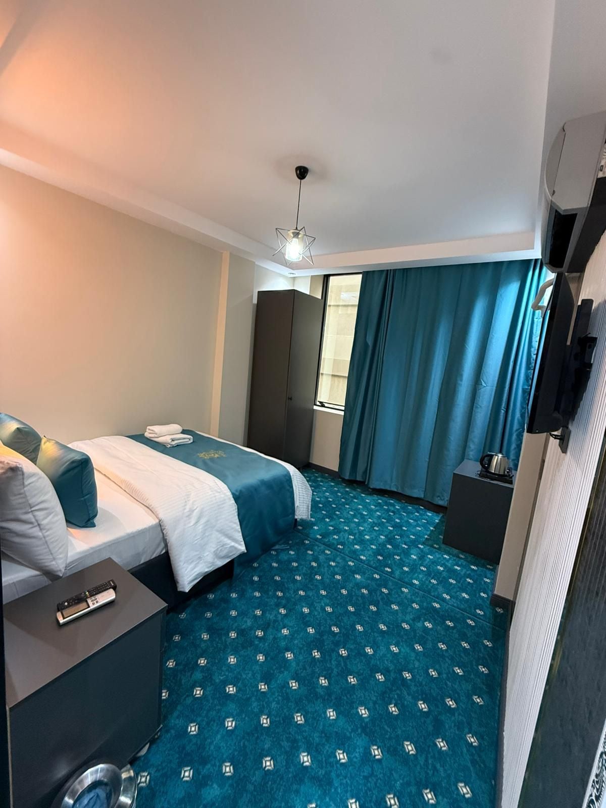 A hotel room with a bed, a desk, a television, and a window with curtains.