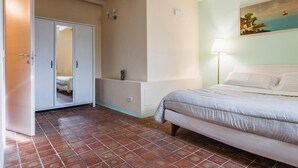 A bedroom with a bed, a wardrobe, a painting, and a lamp.