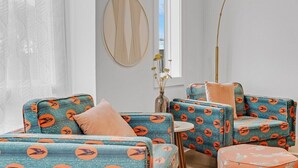 Ein modernes Wohnzimmer mit gemusterten Sofas, einem runden Spiegel und einer Stehlampe.