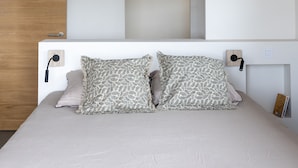 Un dormitorio con cama, lámpara colgante y techo de madera.