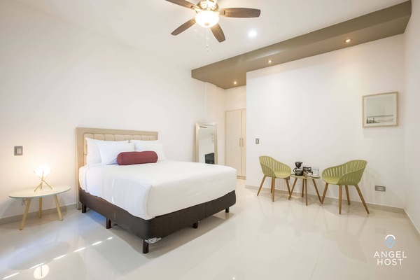 A plush queen bed and a nightstand with a lamp for reading