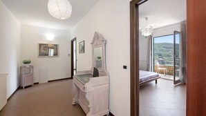 Une chambre avec un lit, une commode, un miroir et un balcon donnant sur un beau paysage.