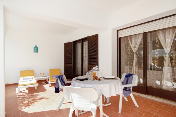 Un coin repas avec une table ronde, des chaises blanches et une fenêtre avec des rideaux.