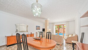 Un vaste espace de vie comprenant une table à manger, des chaises, un canapé et une grande fenêtre donnant sur une piscine.