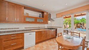 Une cuisine dotée de meubles en bois, d’un lave-vaisselle et d’un coin repas avec une table et des chaises.