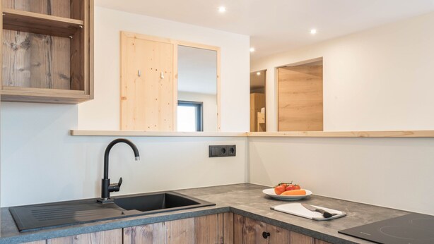 Een moderne keuken met een spoelbak, houten kastjes, een aanrecht en een spiegel.