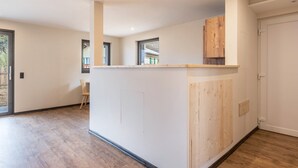 Ruime kamer met houten vloer, een ingebouwde keukenbar en een deur naar een andere ruimte.