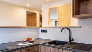 Una cocina con un lavamanos, armarios de madera, una encimera y un espejo.